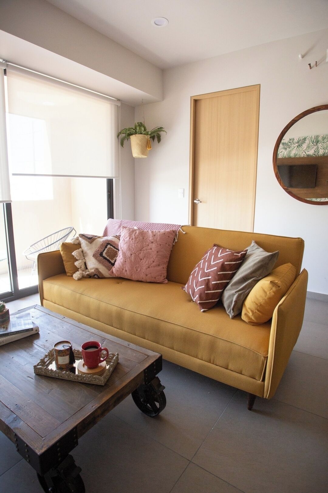 A modern living room with a sofa, a coffee table, a potted plant, and a wooden door.