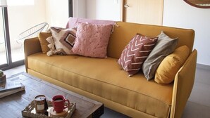 Een moderne woonkamer met een bank, een salontafel, een kamerplant en een houten deur.