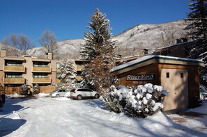 A snow-covered building with a sign reading 'Riverview.' - Riverview Unit 22 | All the Essentials Riverside Condo with Access to Pool & Hot Tub (Aspen)