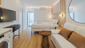 Une chambre d’hôtel moderne équipée d’un téléviseur à écran plat, d’un lit, d’un canapé, d’un miroir rond et d’une machine à laver.