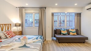 A modern hotel room with a bed, a sofa, and large windows with curtains. - Bright and Fantastic Studio - Suitable for Ambassadors (Madrid)