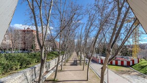 A pathway lined with trees and a brick wall on one side. - Bright and Fantastic Studio - Suitable for Ambassadors (Madrid)
