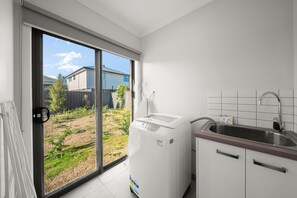 A kitchen with a built-in washer, a sink, and a sliding glass door leading to a backyard.