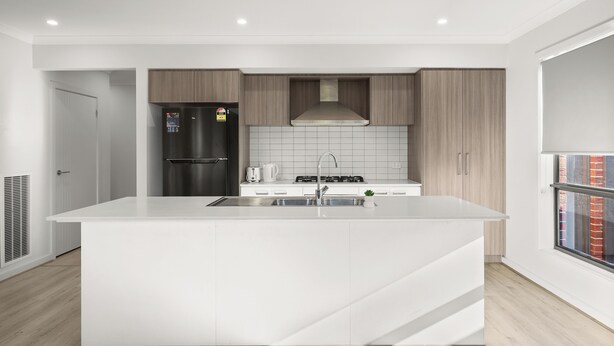 Una cocina moderna con una isla central, electrodomésticos de acero inoxidable y vistas de la ciudad a través de un ventanal.