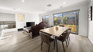 Un salón amplio con una mesa de comedor, sillas, un sofá y una televisión.