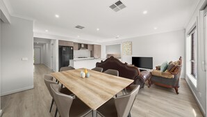 Una sala de estar moderna con una mesa de comedor de madera, sillas de cuero, un sofá y una televisión.