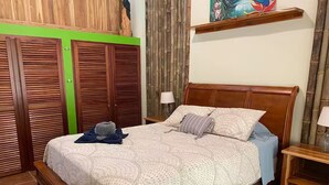 Quarto com cama de madeira, mesa de cabeceira, abajur, guarda-roupa e uma parede verde.