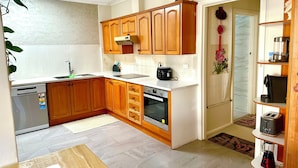 A kitchen with wooden cabinets, a built-in oven, a dishwasher, and a coffee maker.