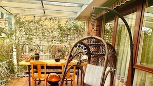 A patio with a swing chair, a wooden table, and chairs.