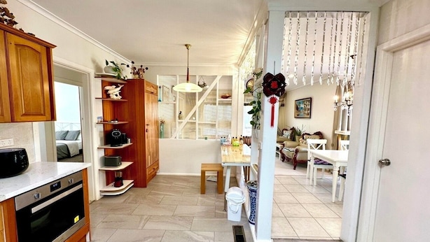 A kitchen with wooden cabinets, a built-in oven, and a dining area with a table and chairs.