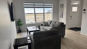Ein Wohnzimmer mit einer Couch, einem Couchtisch und einem an der Wand befestigten Fernseher.