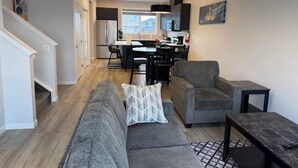 Ein modernes Wohnzimmer mit einem grauen Sofa, einem kleinen Tisch und einer Treppe, die in einen anderen Raum führt.