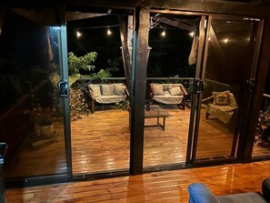 Eine Holzterrasse mit zwei Sofas und einem Tisch, umgeben von Glastüren.