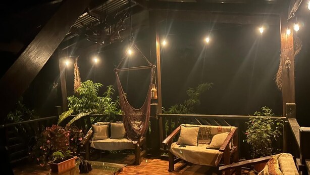 Eine Außenterrasse mit Holzboden, einer Hängematte und zwei Sofas mit Kissen.