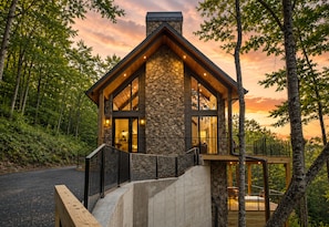 A cabin with a stone exterior, large windows, and a wooden deck. - Discover Pool Paradise w/ Breathtaking Lake Views • HotTub • Fun Games • Privacy (Blue Ridge)
