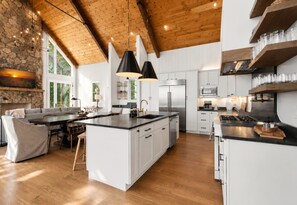 A spacious kitchen with a large island, white cabinetry, and a stone accent wall. - Discover Pool Paradise w/ Breathtaking Lake Views • HotTub • Fun Games • Privacy (Blue Ridge)