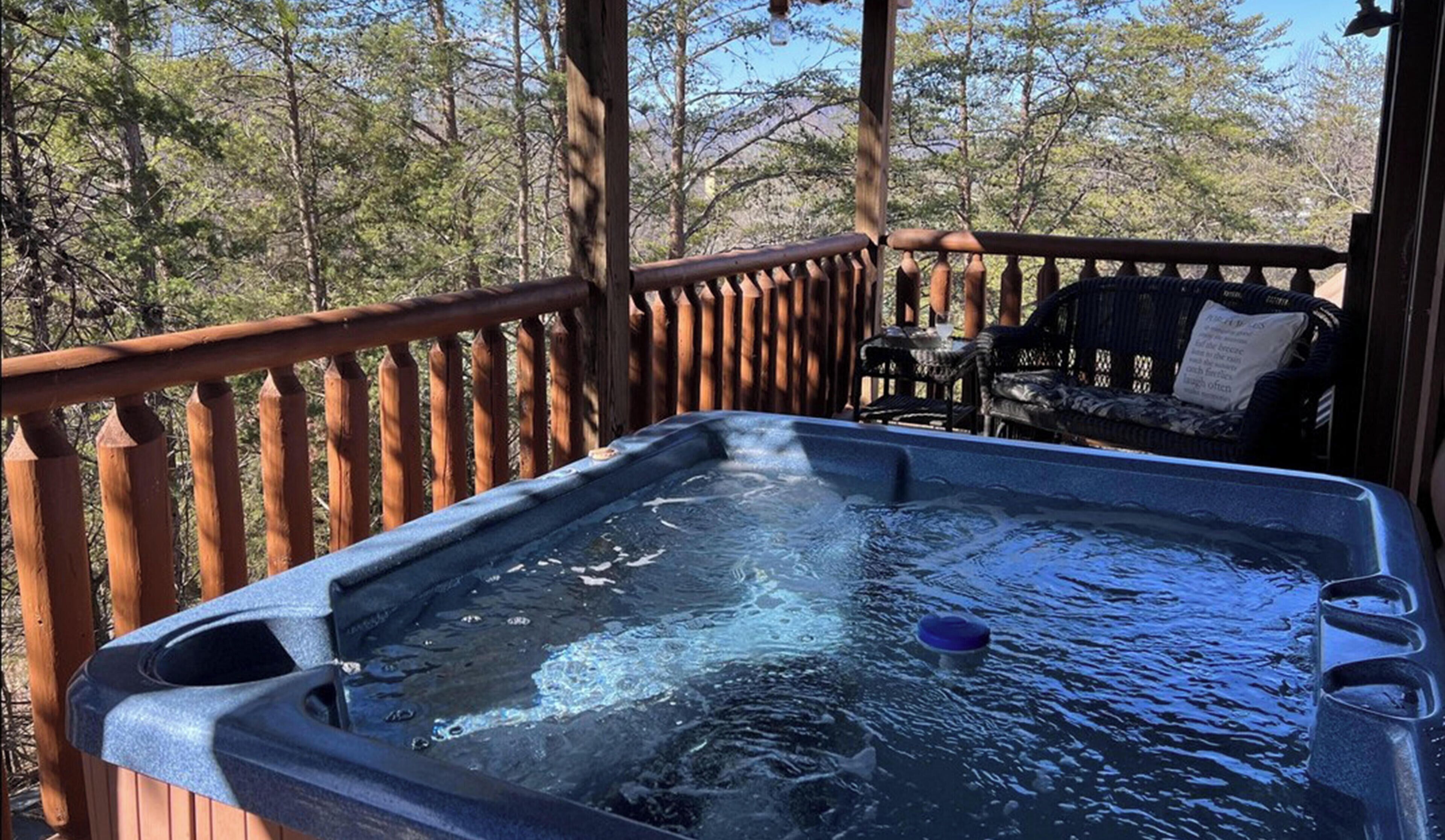 Bubbling private hot tub on the deck surrounded by wooded Smoky Mountain scenery at Airport Runway 33 cabin in Pigeon Forge, Tennessee — just 15 minutes from downtown Pigeon Forge.