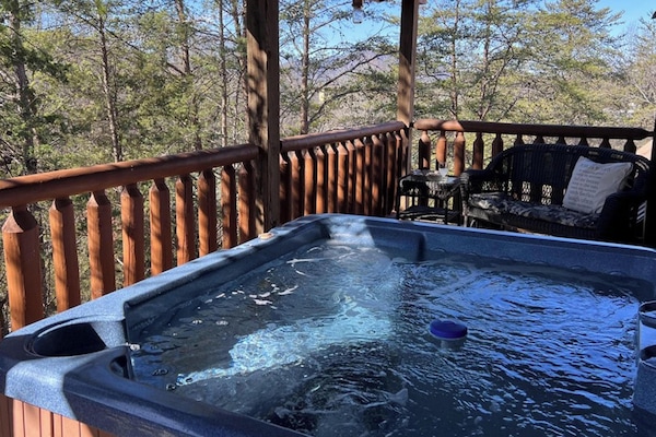 Bubbling private hot tub on the deck surrounded by wooded Smoky Mountain scenery at Airport Runway 33 cabin in Pigeon Forge, Tennessee — just 15 minutes from downtown Pigeon Forge.
