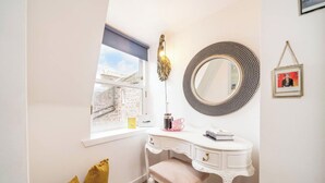 A white vanity with a round mirror, a small window, and a decorative wall hanging. - The Hideaway Cosy Seaside Getaway in Stonehaven (Stonehaven)