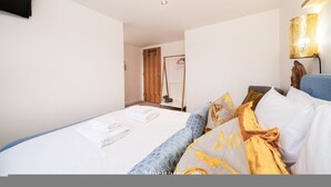 A hotel room with a bed, a wall-mounted TV, a lamp, and a door leading to a bathroom. - The Hideaway Cosy Seaside Getaway in Stonehaven (Stonehaven)