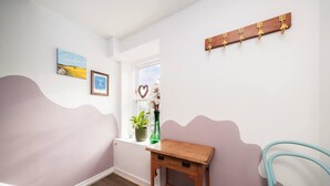 A hallway with a wooden bench, a green vase with flowers, a heart-shaped decoration, and a coat rack with hooks. - The Hideaway Cosy Seaside Getaway in Stonehaven (Stonehaven)