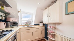 A kitchen with a window, a stove, and cabinets. - The Hideaway Cosy Seaside Getaway in Stonehaven (Stonehaven)