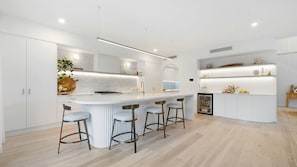Eine moderne Küche mit einer zentralen Kochinsel, Barhocker und einem eingebauten Kühlschrank.