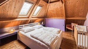 Une chambre avec un plafond en pente, un lit, une chaise et une armoire violette.