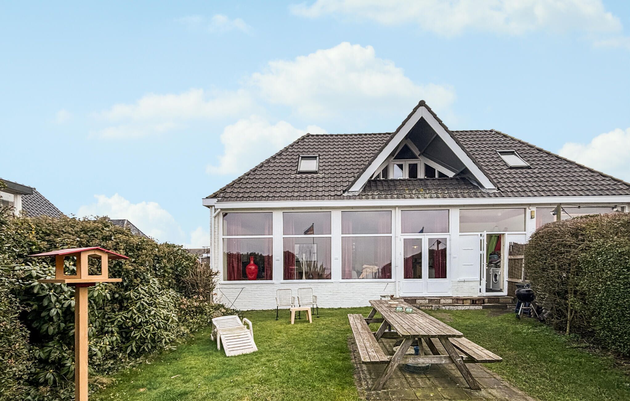 A house with a large glass front, a wooden deck, and a picnic table.