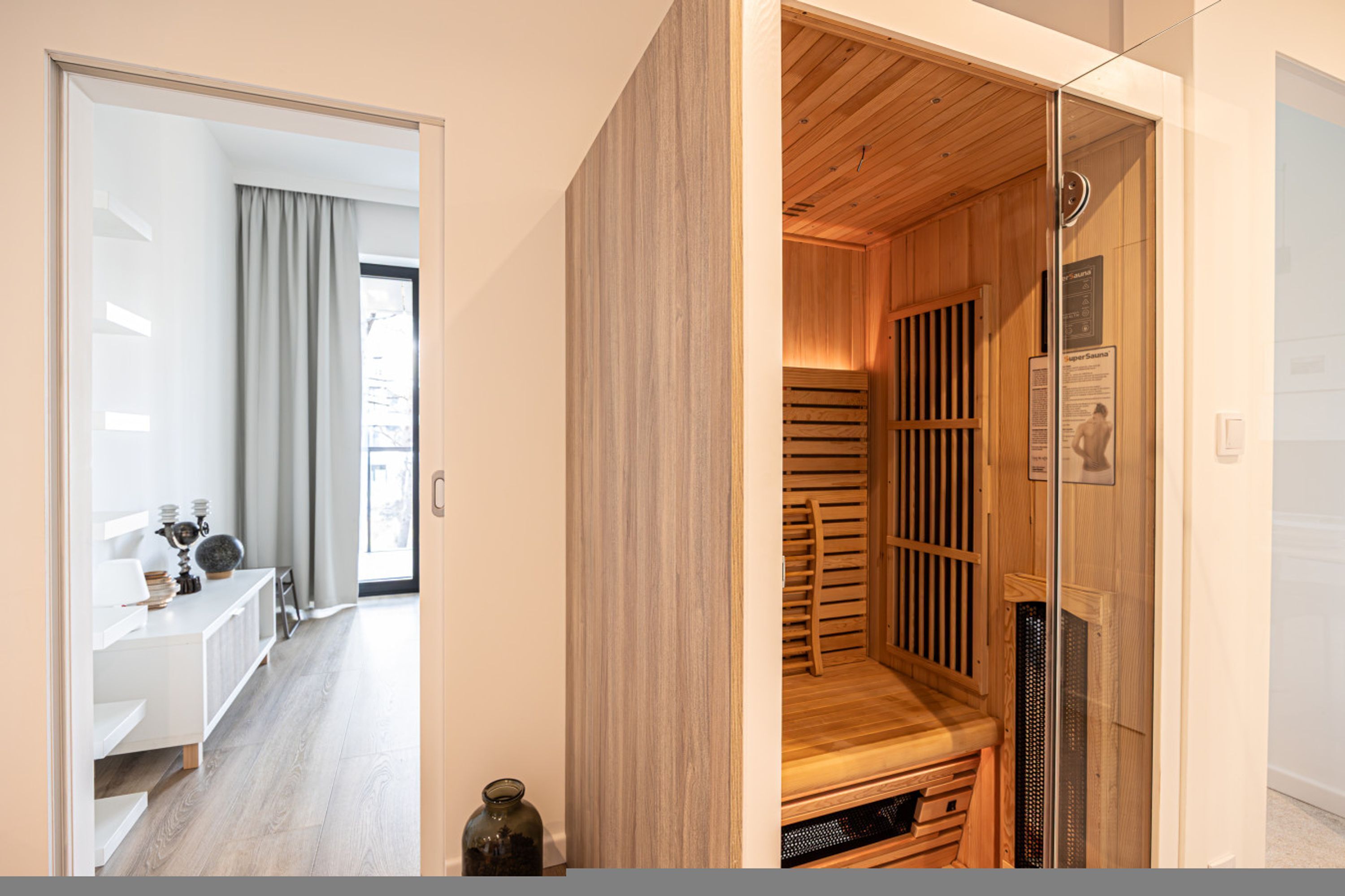 A modern interior with a wooden sauna, a white reception desk, and a view through a glass door.