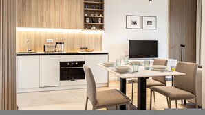 Een moderne keuken met inbouwapparatuur, een eethoek met een televisie en een minimalistische inrichting.