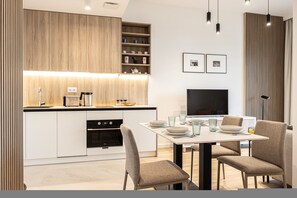 Eine moderne Küche mit integrierten Geräten, ein Essbereich mit Fernseher und eine minimalistische Einrichtung.