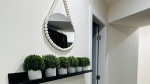 Un pasillo con un estante negro que sostiene pequeñas plantas en macetas y un espejo decorativo.
