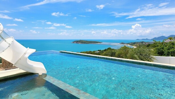 Una piscina infinita amb una vista clara de l'oceà i una illa allunyada.