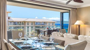 Una camera d'albergo con balcone, un tavolo da pranzo per due persone e un divano.