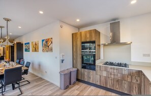 A modern kitchen with wooden cabinets, a built-in oven, and a gas stove. - Charming Marsaskala Stay Balcony Seafront Walks (Marsaskala)