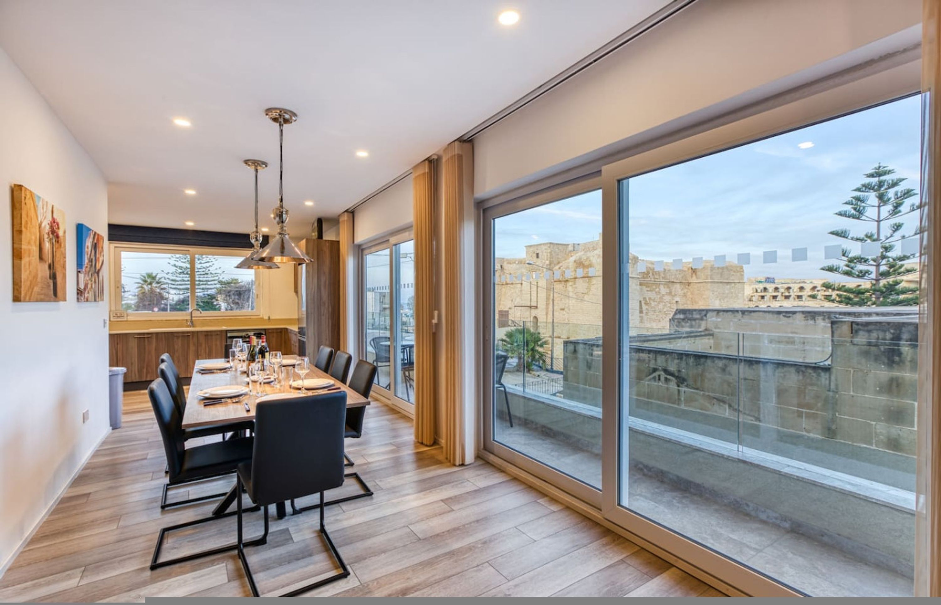 A modern dining area with a large table, chairs, and pendant lighting.