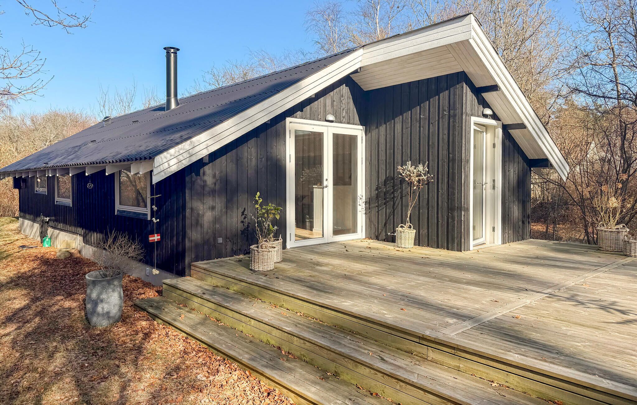Une cabane en bois avec un porche, une cheminée et un drapeau.