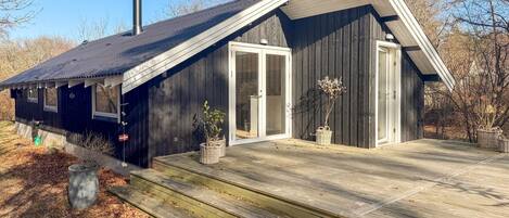 Une cabane en bois avec un porche, une cheminée et un drapeau.