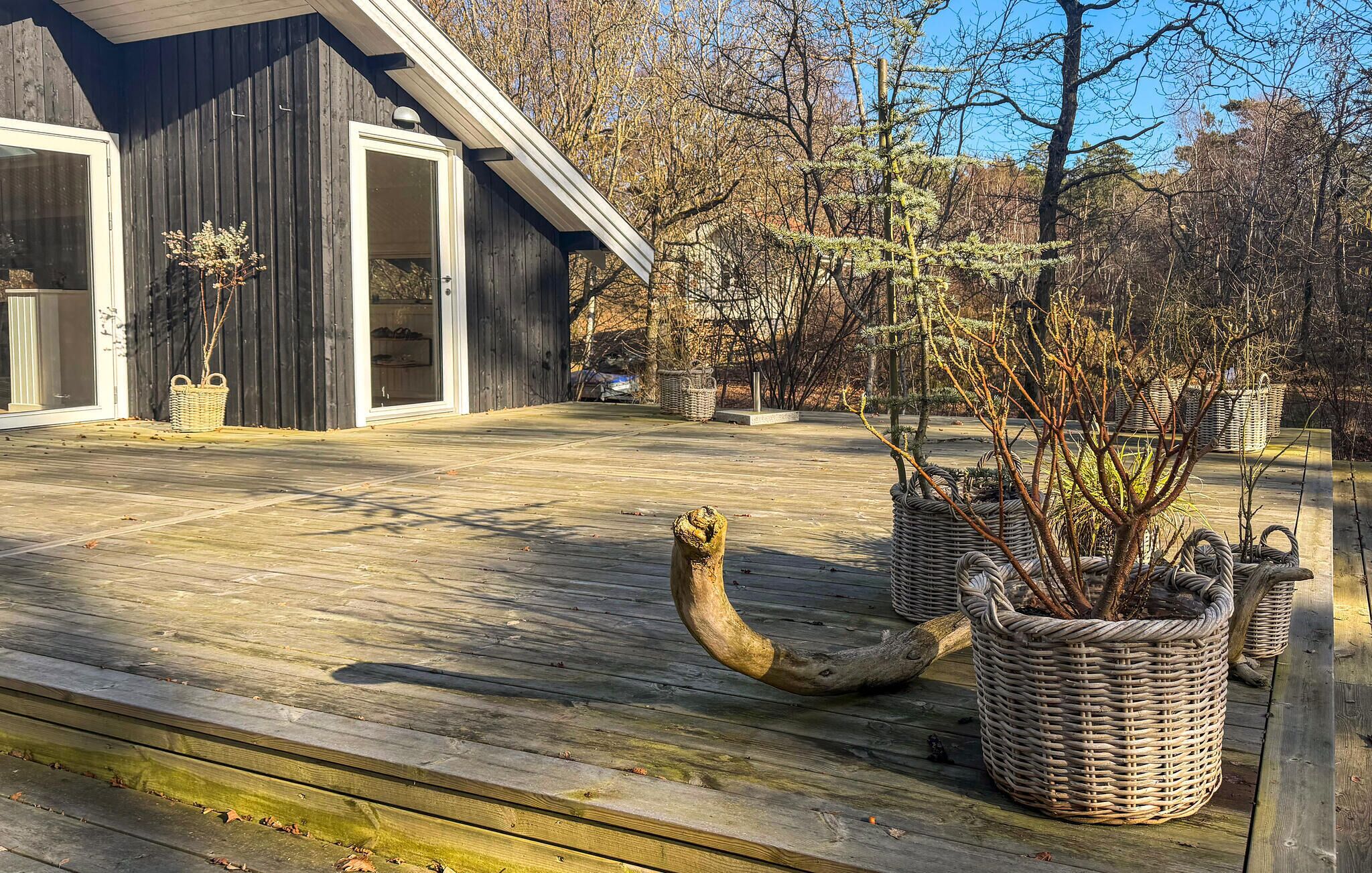 A wooden deck with a large curved wooden sculpture, wicker baskets, and a building with a glass door.