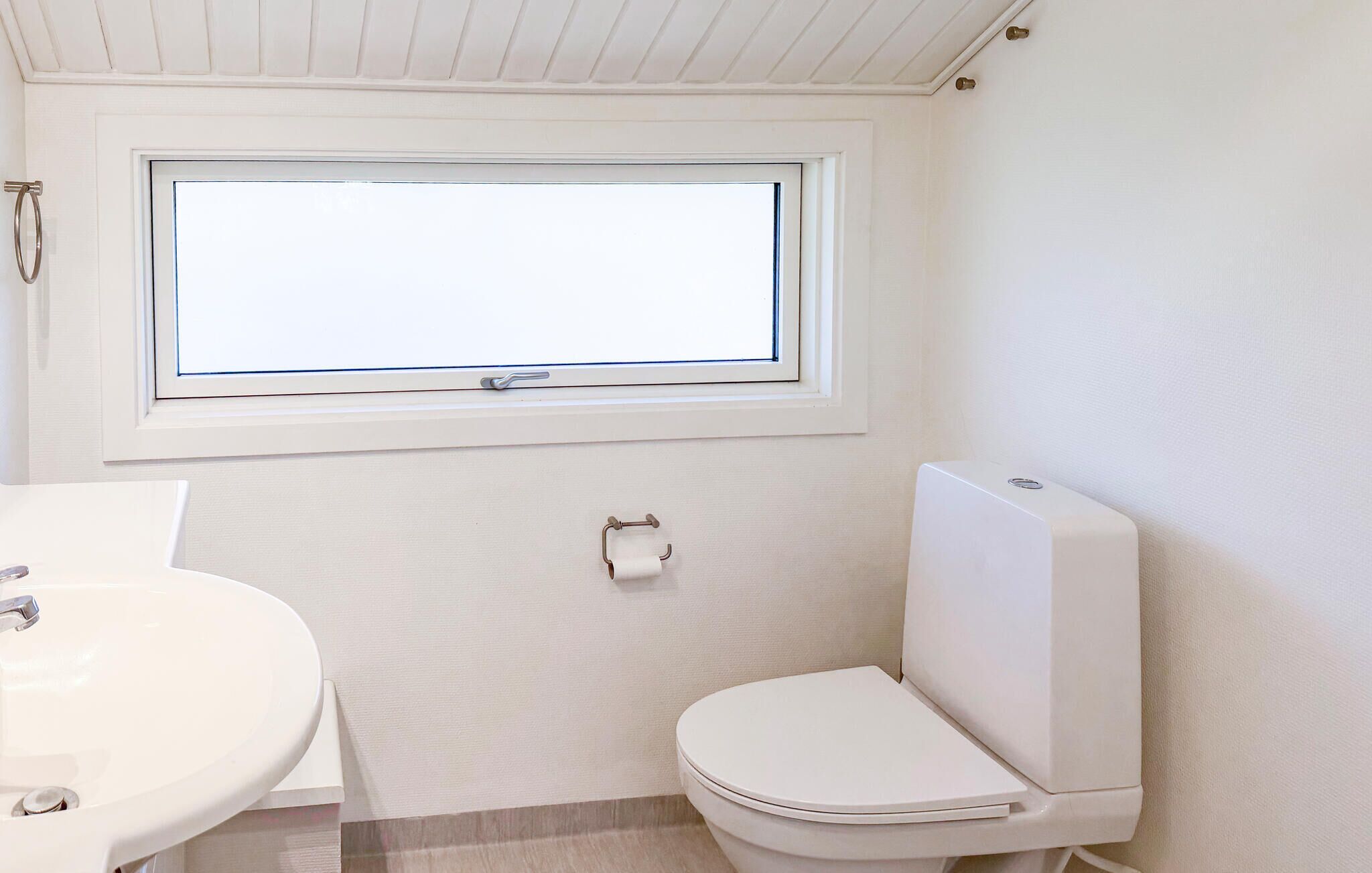 Une salle de bain avec des toilettes, un lavabo et une fenêtre.