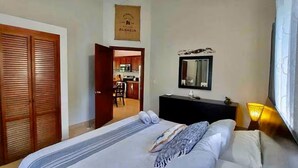 Een hotelkamer met een bed, een dressoir, een spiegel en uitzicht op de keuken.