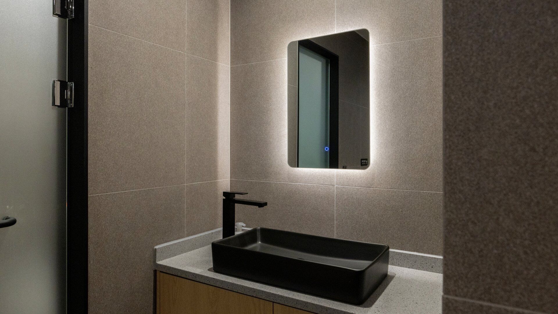 A bathroom with a rectangular sink, a mirror, and a door.