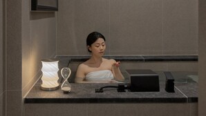 A person in a spa setting with a towel, a massage chair, and a water feature. - Anook Ryokan Hotel Eunpyeong Bulgwang (Seoul)