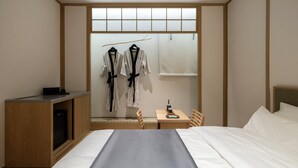 A hotel room with a bed, a desk, a TV, and a wardrobe with clothes hanging. - Anook Ryokan Hotel Eunpyeong Bulgwang (Seoul)