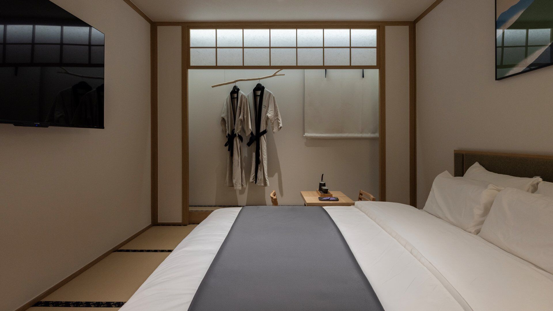 Una habitación de hotel con cama, televisión, armario y una mesita con una taza.