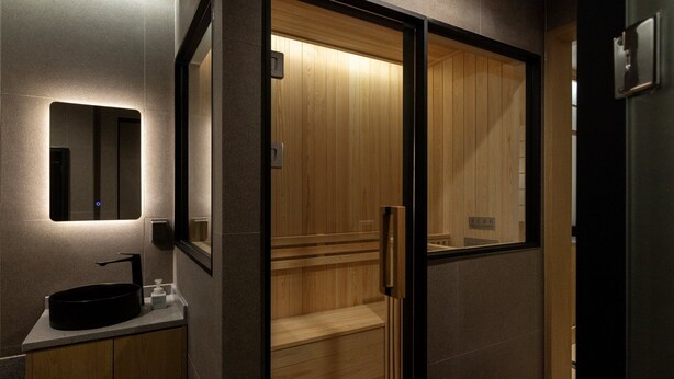 A modern bathroom with a wooden vanity, a mirror, and a wooden door. - Anook Ryokan Hotel Eunpyeong Bulgwang (Seoul)