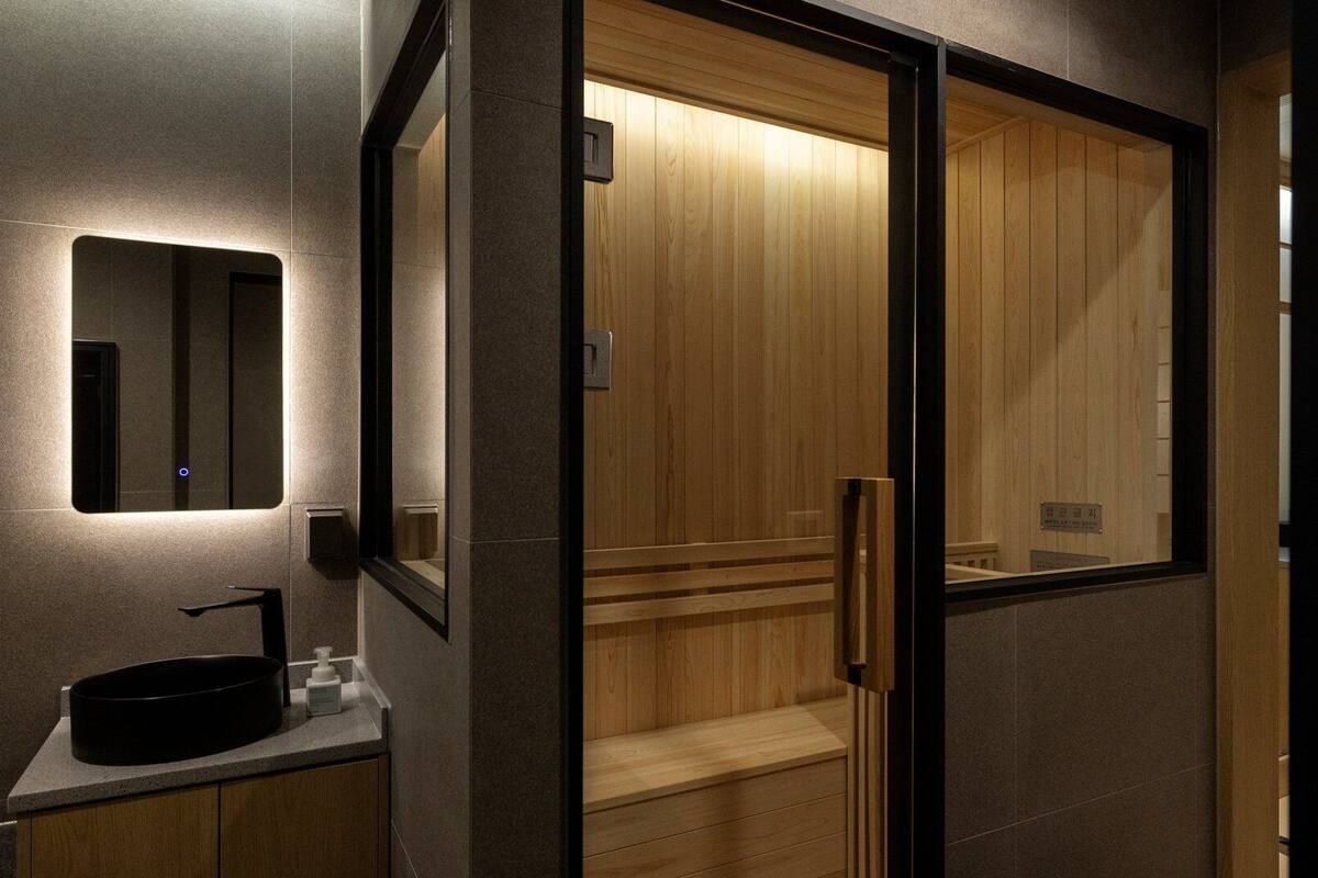 A modern bathroom with a wooden vanity, a mirror, and a wooden door.