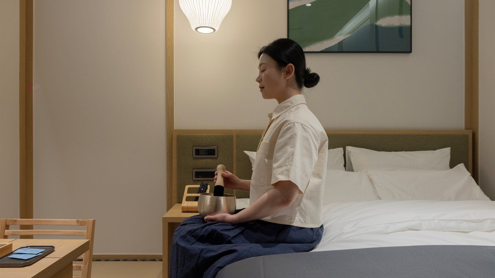 A hotel room with a bed, a nightstand with a lamp, a microwave, and a phone.
