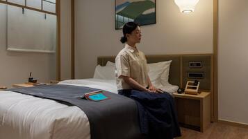 Una habitación de hotel con cama, mesita de noche, lámpara y un cuadro en la pared.